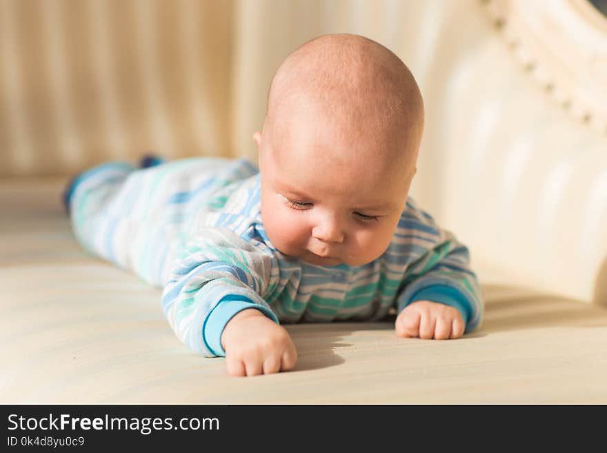 Baby boy lying on a sofa in sunny room.