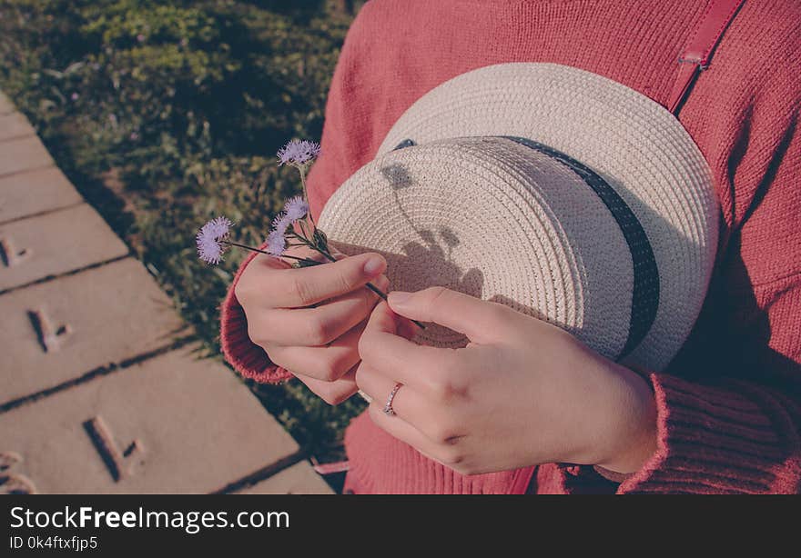 Person Wearing Sweater Holding Flower and Hat