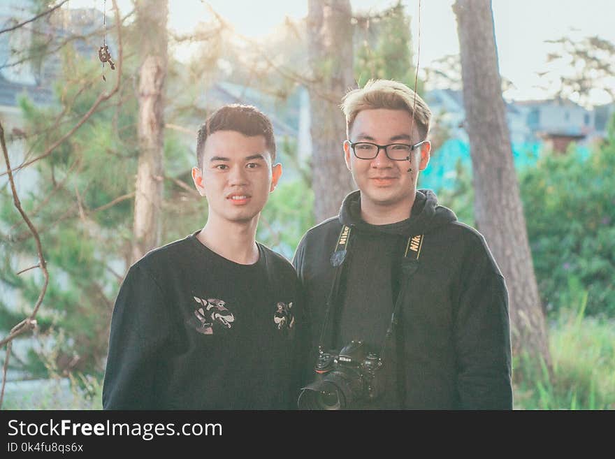 Two Men Standing Near Tree Trunks