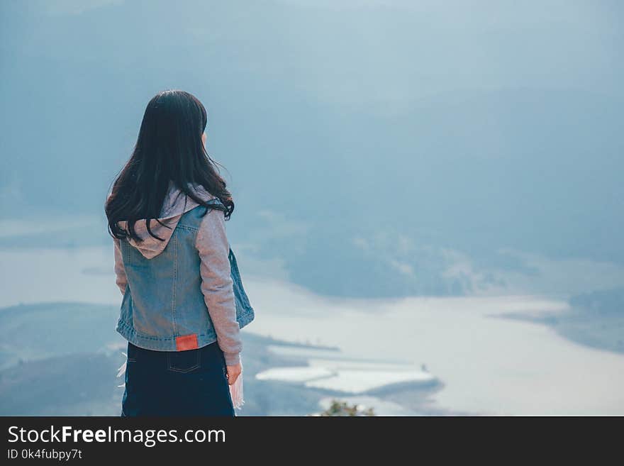 Woman in Gray and Blue Zip-up Hoodie Standing on the Cliff