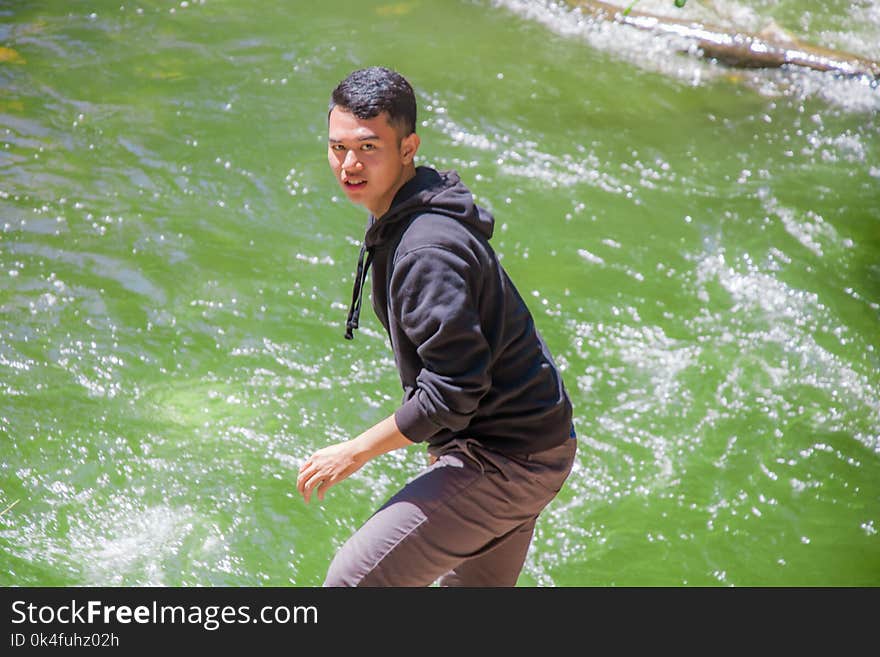 Man in Black Hoodie Standing in Front of Body of Water