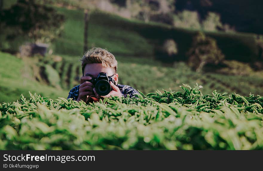 Shallow Focus Photography of Man Holding Dslr Camera