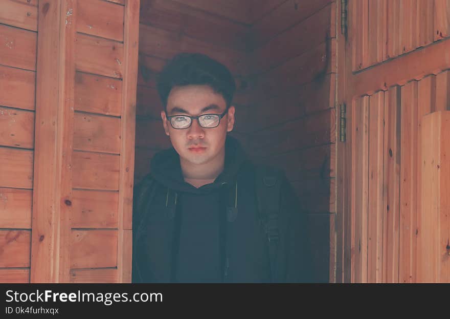 Man Wearing Eyeglasses and Hoodie Jacket in Wooden Room