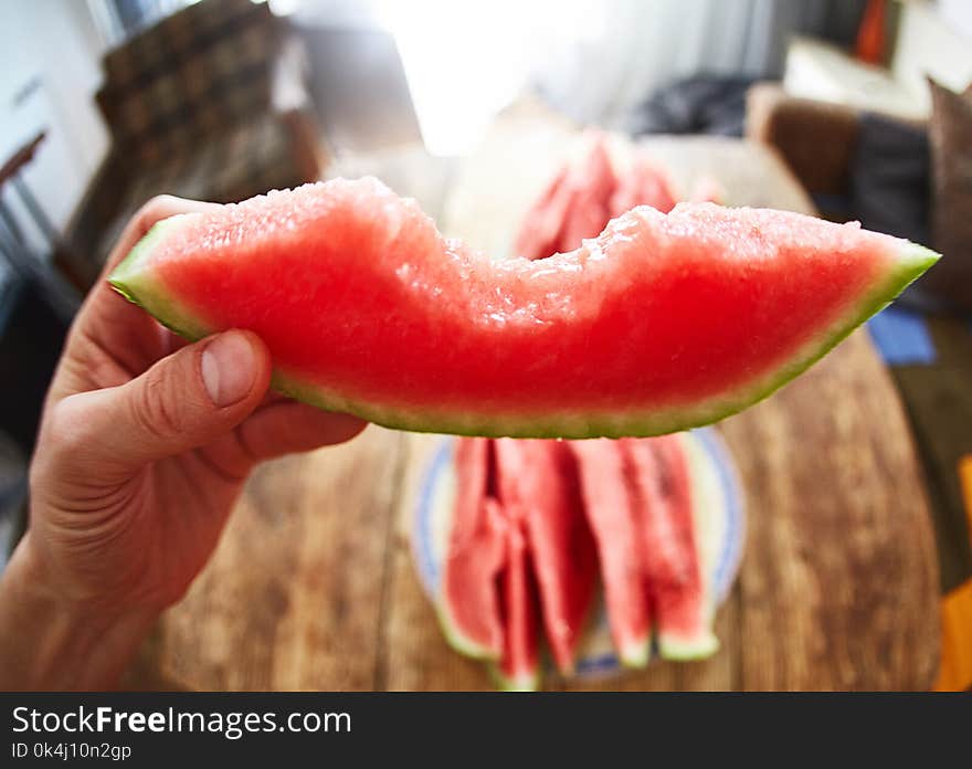 View of slice of ripe juicy watermelon in the hand on the wooden table background . first-person view. View of slice of ripe juicy watermelon in the hand on the wooden table background . first-person view