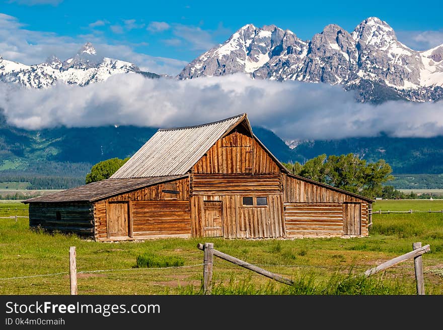 Old mormon barn in Grand Teton Mountains with low clouds. Grand Teton National Park, Wyoming, USA. Old mormon barn in Grand Teton Mountains with low clouds. Grand Teton National Park, Wyoming, USA.