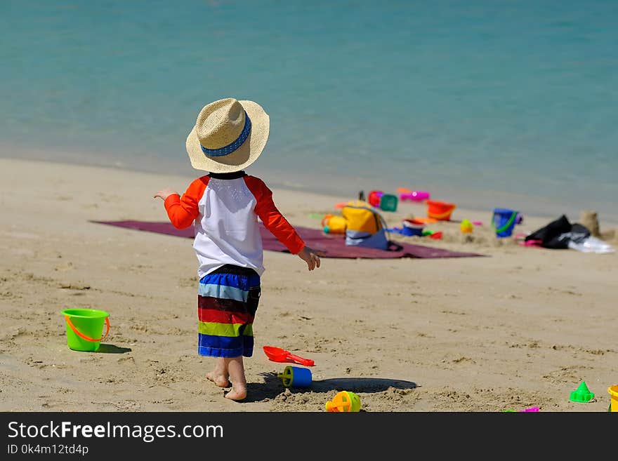 Two year old toddler boy playing with beach toys on beach. Two year old toddler boy playing with beach toys on beach