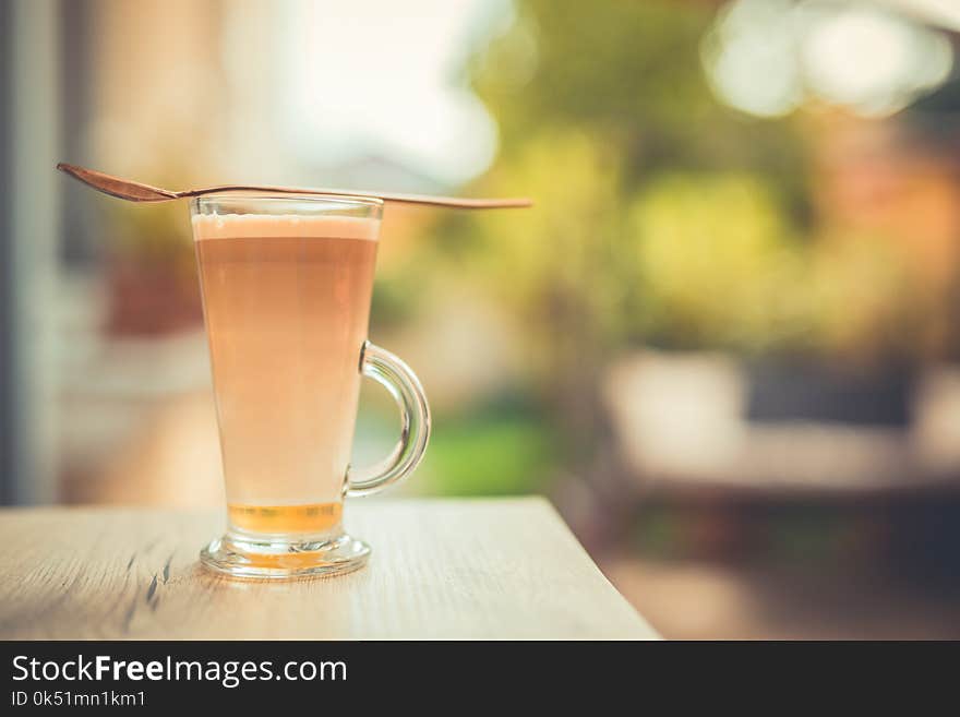 Morning calmness and fresh coffee latte in glass mug on wooden table and natural garden background. Morning calmness and fresh coffee latte in glass mug on wooden table and natural garden background