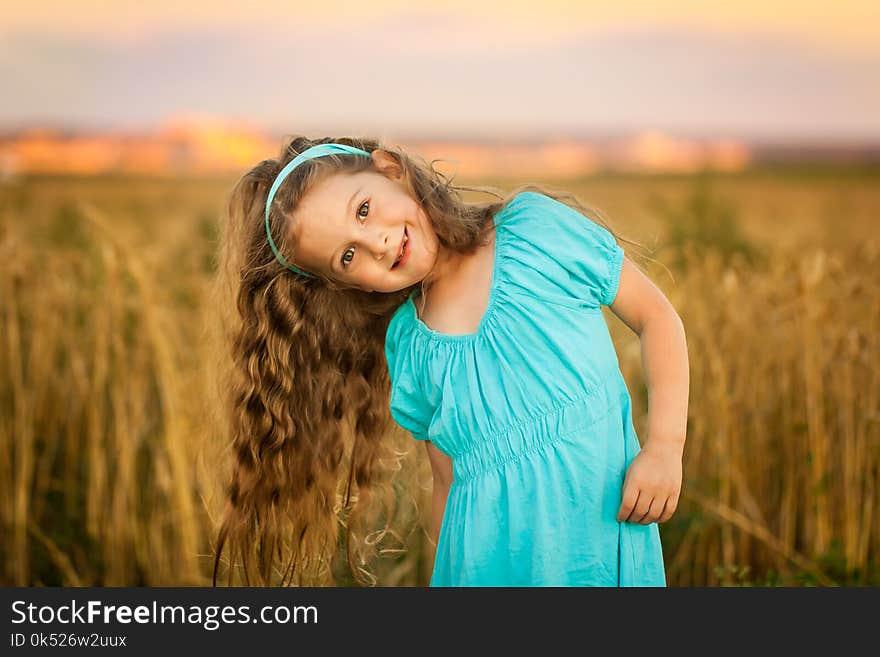 Happy girl in wheat field on warm and sunny summer evening