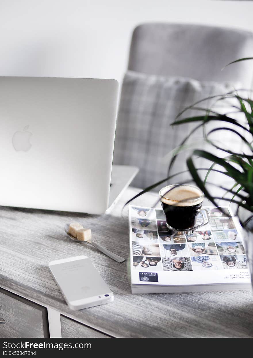 Silver Iphone Beside Book Under Cup Beside Silver Macbook