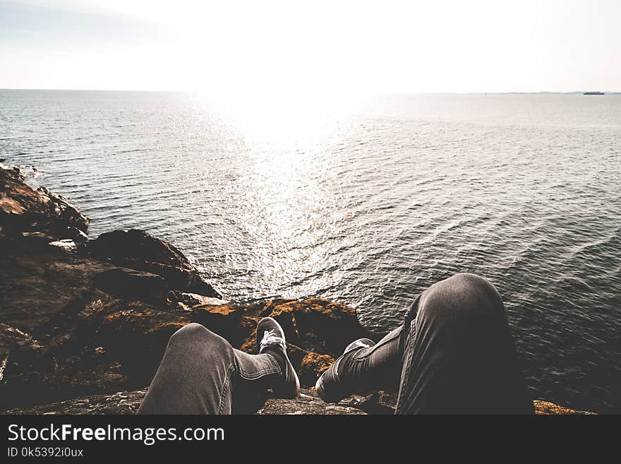 Photo of Person Sitting on Cliff