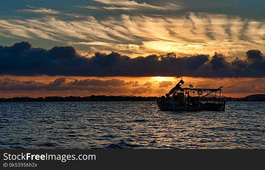 Silhouette Photo of Boat on Ocean during Golden Hour