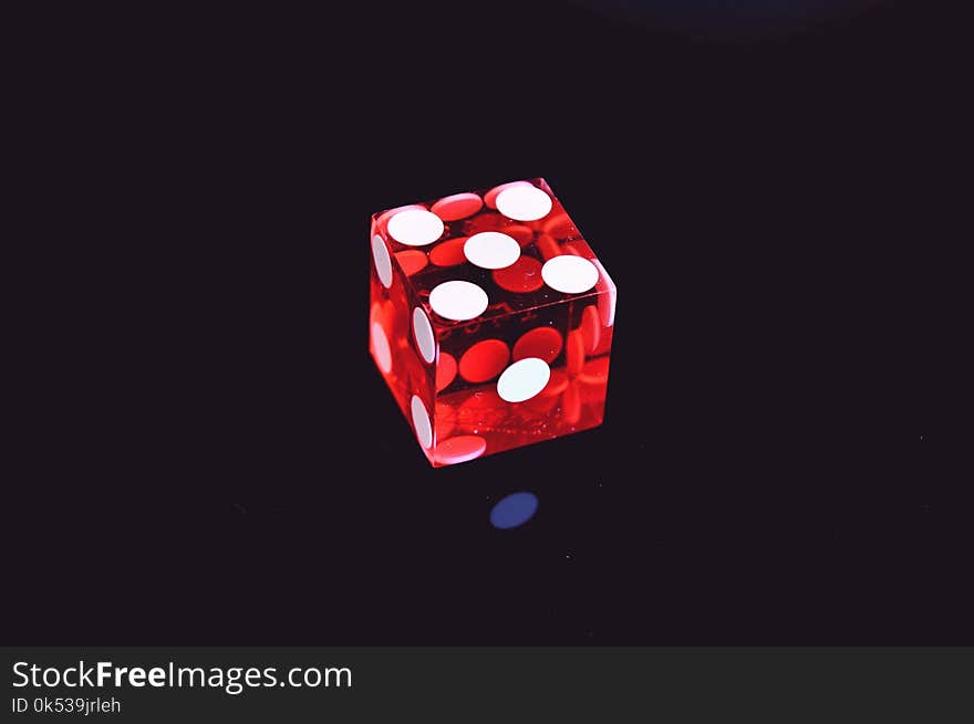 Red Translucent Die on Top of Black Surface