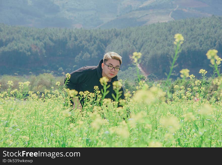 Man in Black Pullover Hoodie Standing in Flower Field