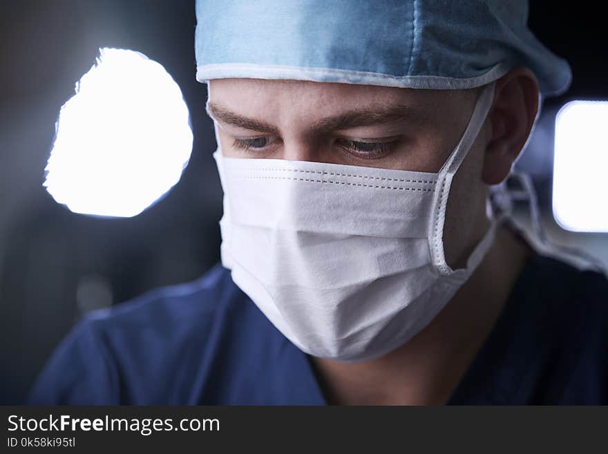 Male surgeon looking down, head and shoulders