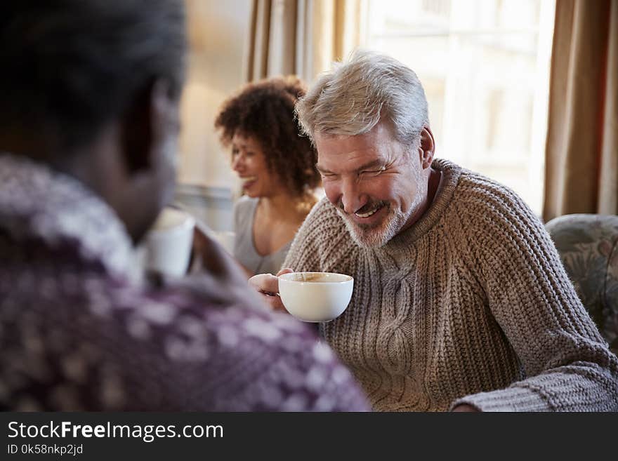Middle Aged Man Meeting Friends Around Table In Coffee Shop
