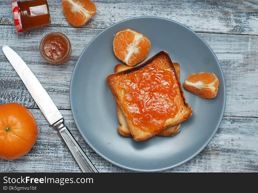 Fresh Toasts with Homemade Orange Jam on Gray Plate over Wooden Background.