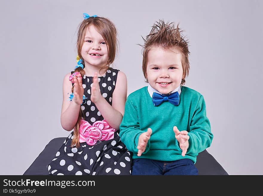 Beautiful little boy and girl clap their hands and smile