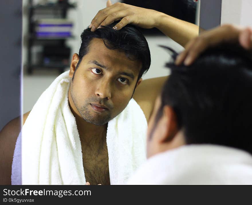 Indian asian man looking after his appearance in front of a mirror beauty styling lifestyle.hair styling