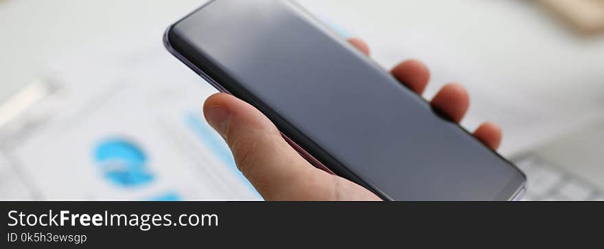 A businessman holds a new smartphone in his hand The mobile application market shows a display you can insert your image for advertising or financial statistics.