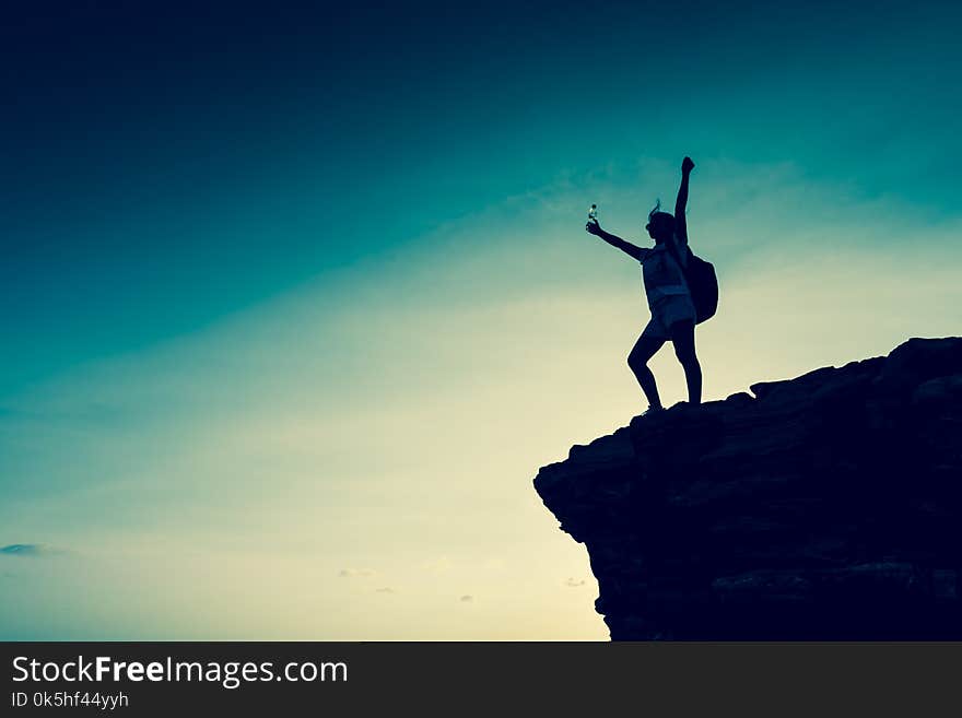 Silhouette sporty woman on the cliff. Sunset and high mountain. Business Success and goal. Silhouette sporty woman on the cliff. Sunset and high mountain. Business Success and goal.