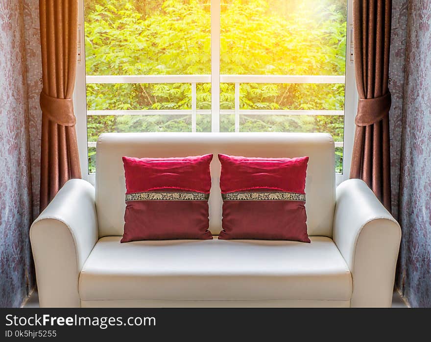 Double red cushions on white sofa in living room inside windows. Double red cushions on white sofa in living room inside windows