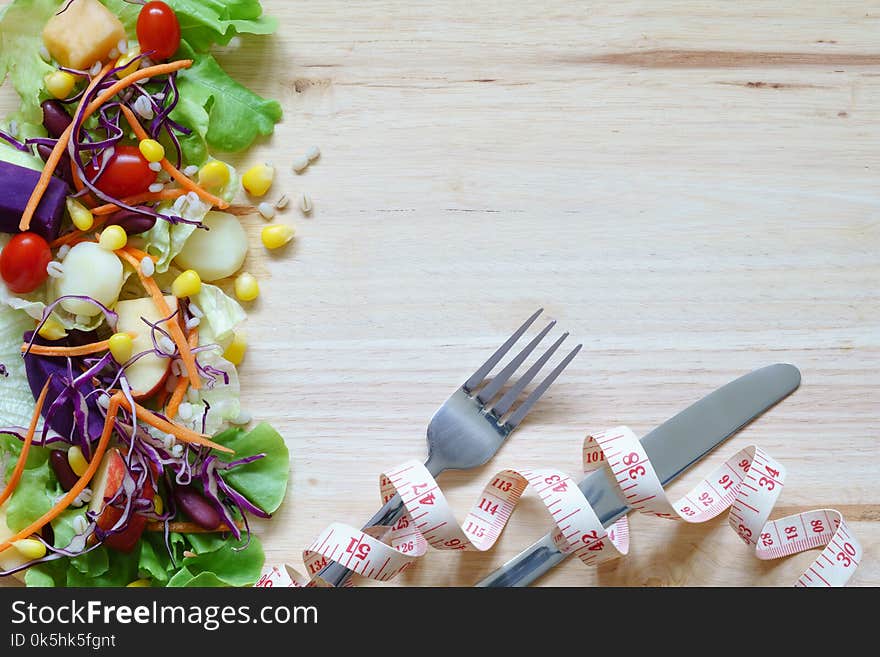 Fresh healthy salad with mixed greens vegetables and fruits on w