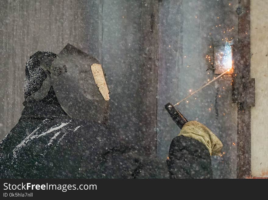 Welding a man repairs a garage outdoors. Welding a man repairs a garage outdoors