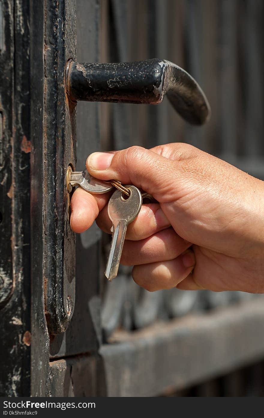 Woman opens the metal door using the key. Selective focusing. Woman opens the metal door using the key. Selective focusing