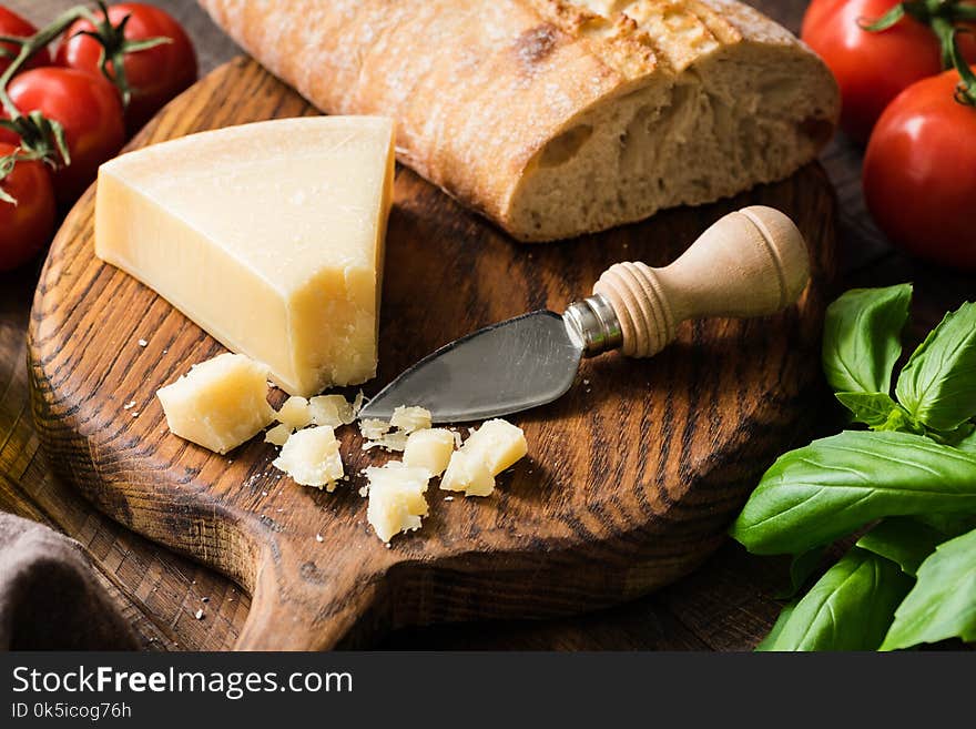 Parmesan cheese and fresh ciabatta bread on wooden cutting board, closeup view, selective focus