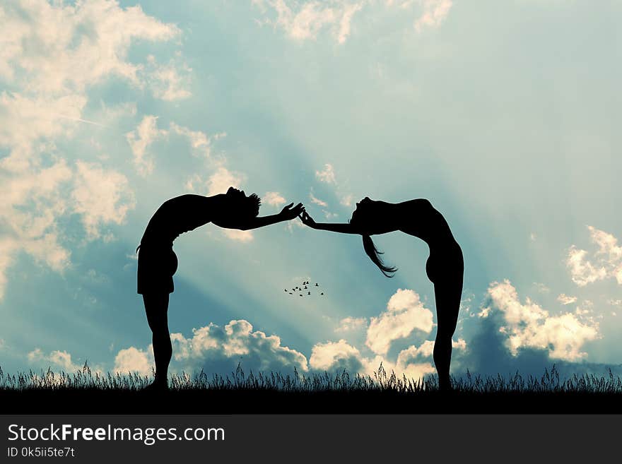 Couple makes yoga poses at sunset