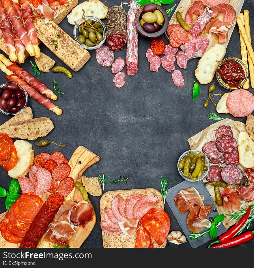 Italian meat appetizer snack set. Variety salami, prosciutto, bread sticks, olives, capers on concrete background. Italian meat appetizer snack set. Variety salami, prosciutto, bread sticks, olives, capers on concrete background