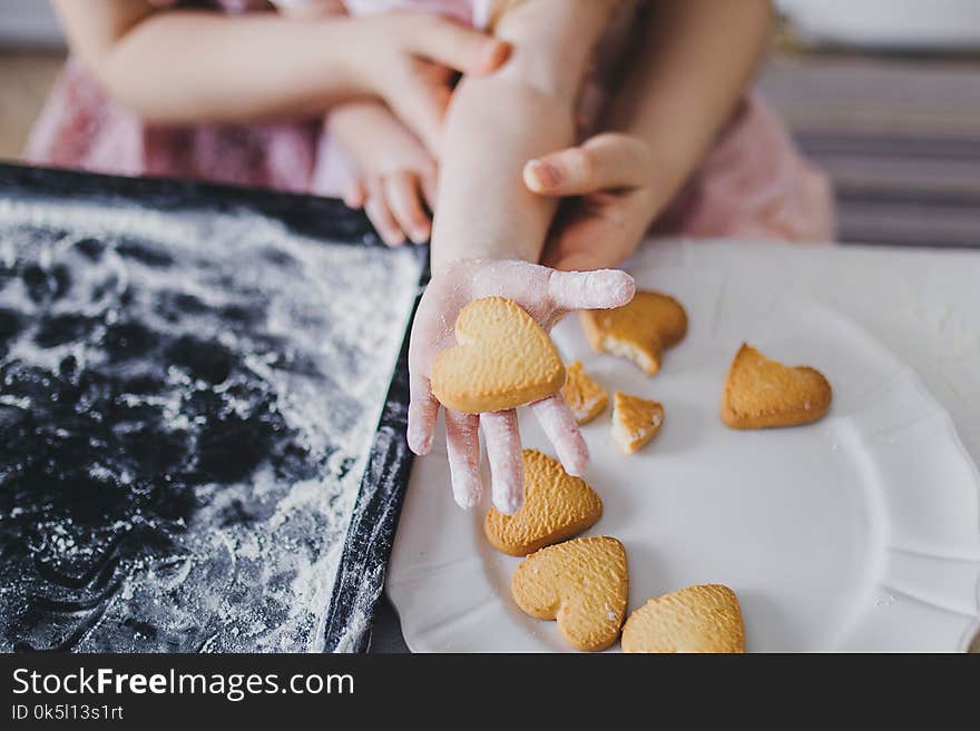 Mom and daughter lay out cookies on a white plate. Mom and daughter lay out cookies on a white plate