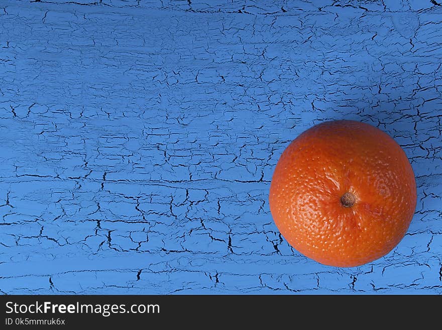 Orange mandarin on a blue background with craquelures. View from above. Close-up, copy space