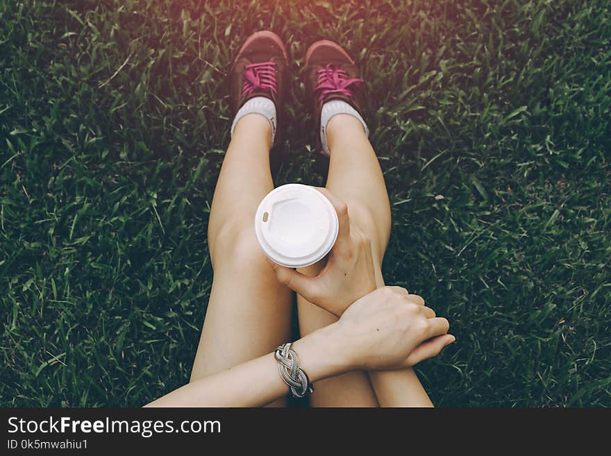 Sport young asian woman sitting on grass, drinking coffee. Resting Runner. Vintage filter.