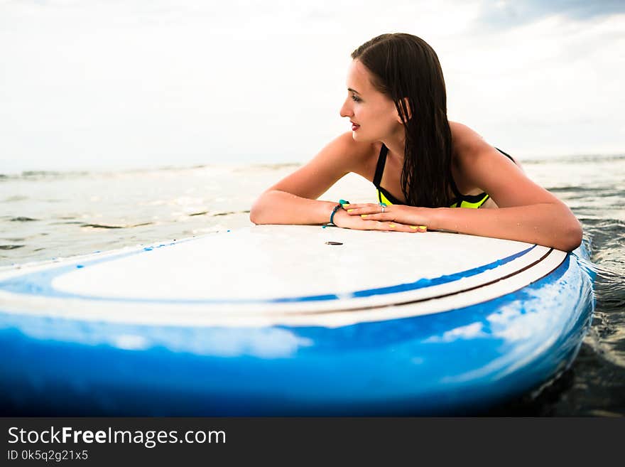 Woman surfer paddling prone on surfboard to the open sea for surfing. Woman surfer paddling prone on surfboard to the open sea for surfing
