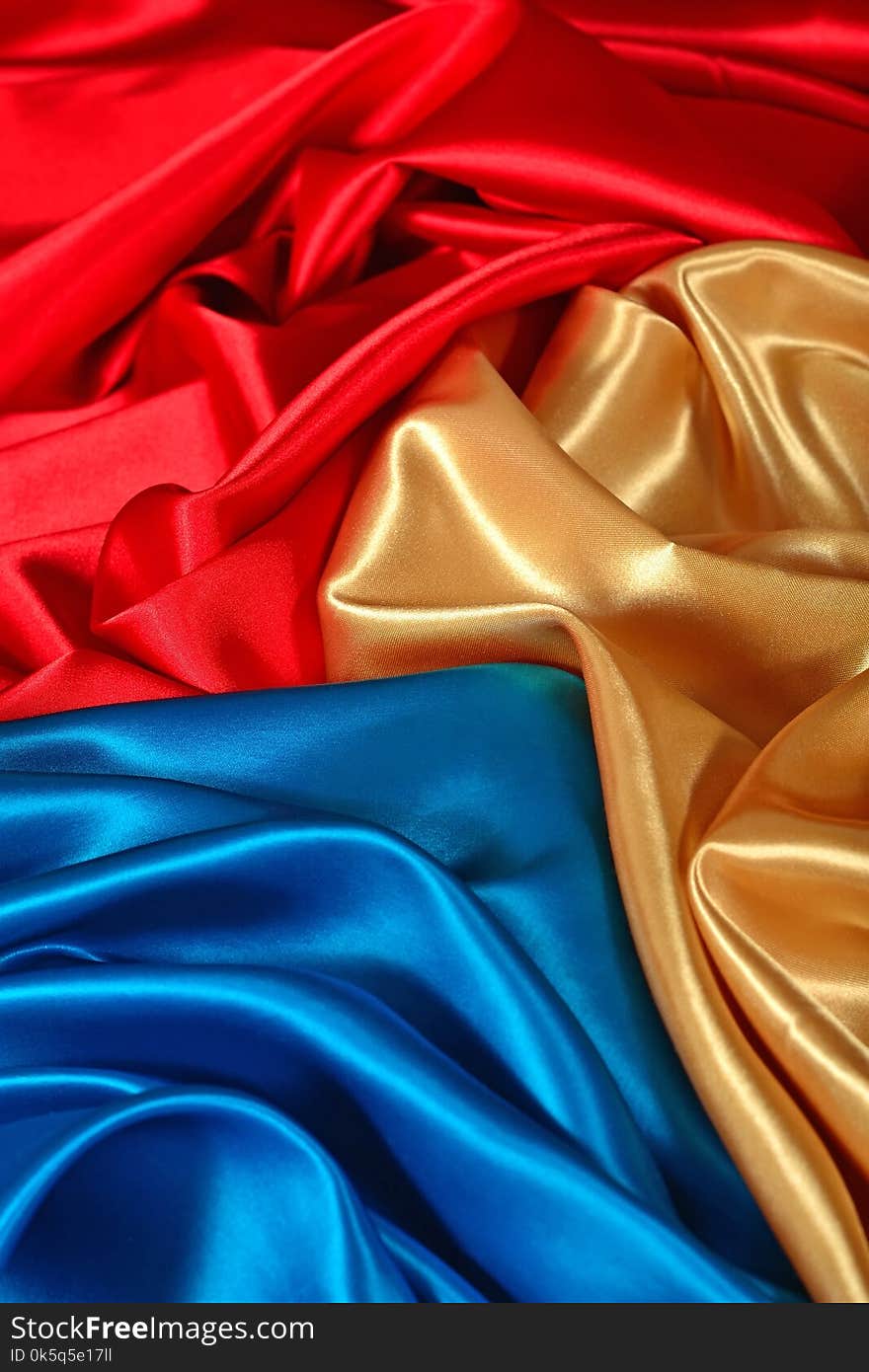 Natural golden, blue and red satin fabric as background texture. Natural golden, blue and red satin fabric as background texture