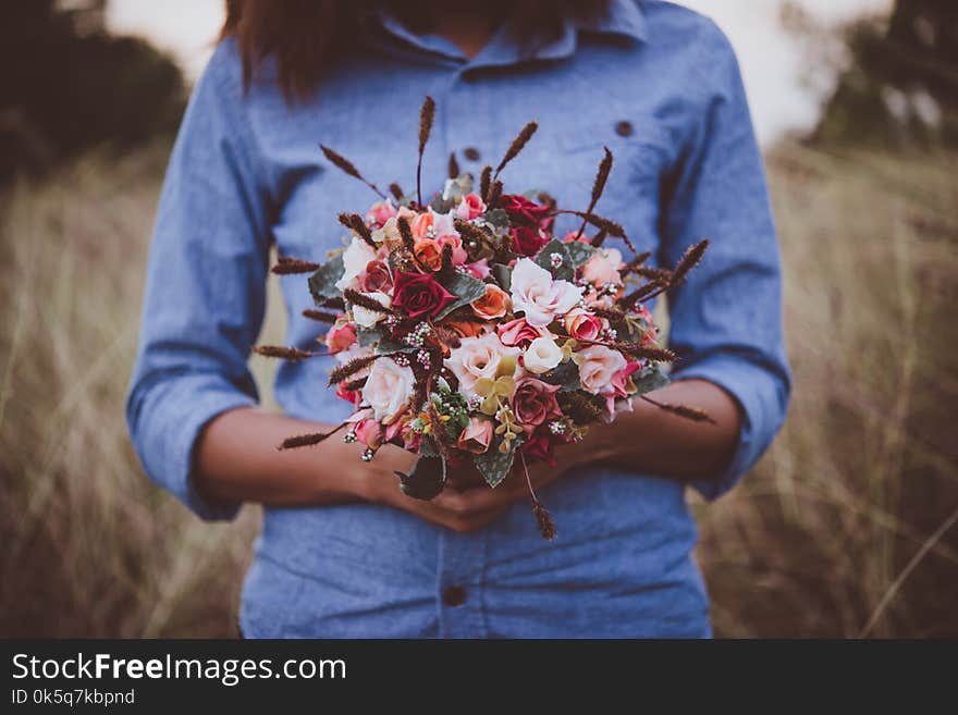 Young hipster woman in field holding a bouquet of red rose, summer holiday. Freedom enjoy lifestyle. Vintage tone.