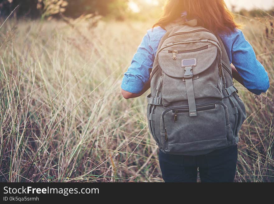 Vintage tone images of beautiful young hipster woman with backpack walking on meadow. Portrait of hiker girl outdoor.