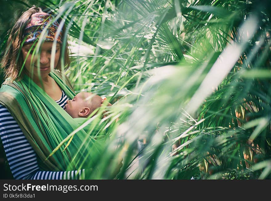 A young mother with a baby in a sling is travelling in the jungle