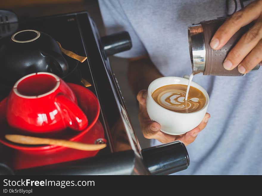 Pouring cream milk into a cup of coffee making latte art. Pouring cream milk into a cup of coffee making latte art