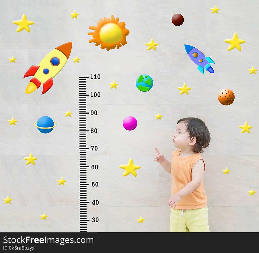 Closeup happy kid stand and point to scale of measure height with cute cartoon at the marble stone wall textured background in growth of kid concept. Closeup happy kid stand and point to scale of measure height with cute cartoon at the marble stone wall textured background in growth of kid concept