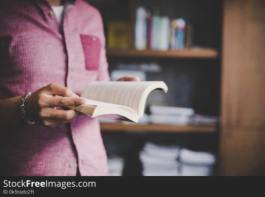 Young Hipster Man Reading Book In Library.