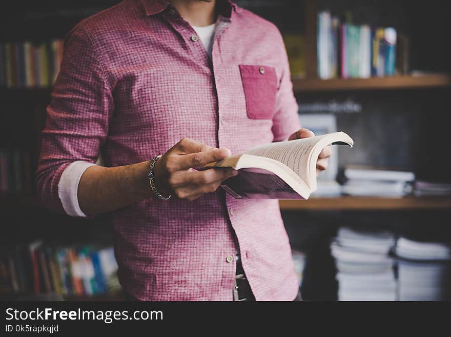 Young hipster man reading book in library background. Young hipster man reading book in library background