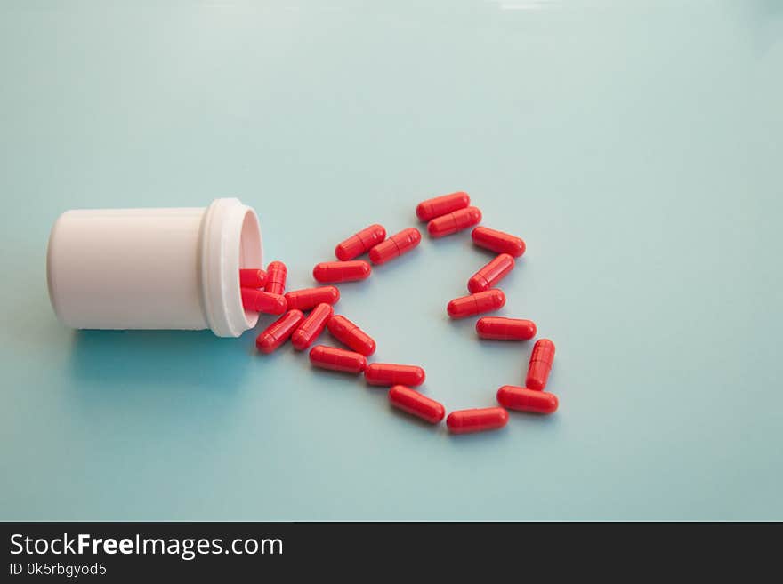 Assorted pharmaceutical medicine pills, capsules for the treatment of heart disease on blue background. Heart shape and bottle of pills. Copy space for text.