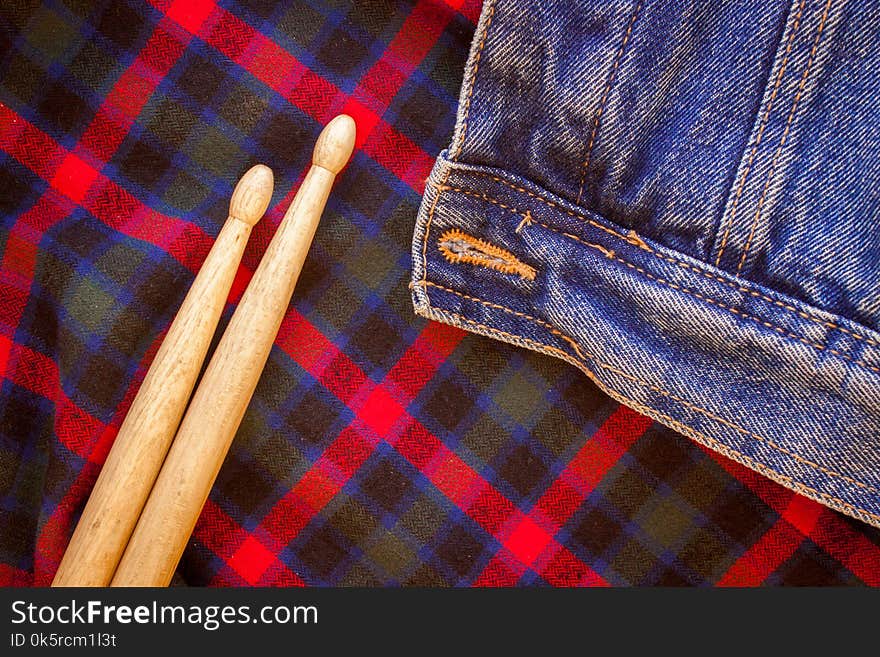 Two drum sticks of oak lie on the fabric of a Scottish cage and jeans. Two drum sticks of oak lie on the fabric of a Scottish cage and jeans