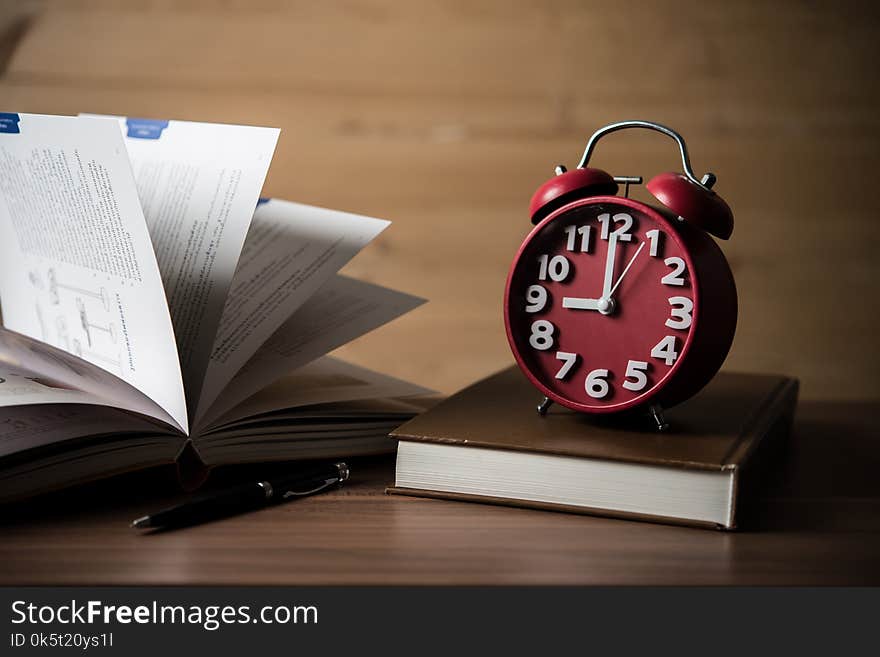 Books and alarm clock on wooden table. Education concept.