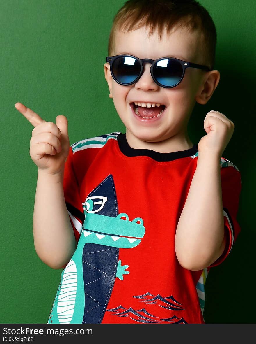 Preschool Boy Kid Standing In Sunglasses In Shorts And T-shirt Pointing Finger