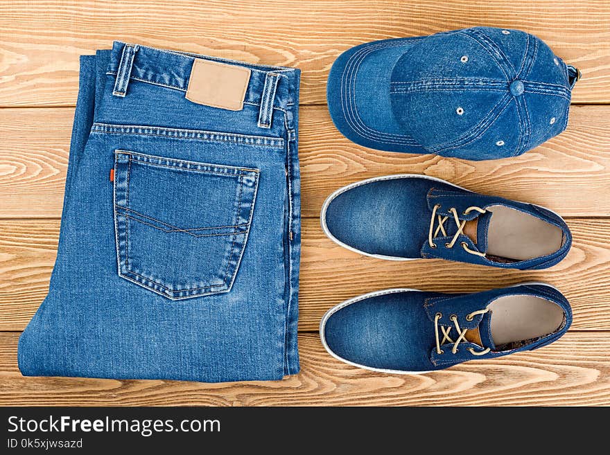 Jeans, Shoes And A Cap On A Wooden Background