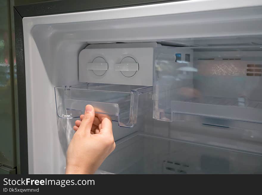 Woman hand open clear plastic ice container drawer in new refrigerator. Woman hand open clear plastic ice container drawer in new refrigerator.