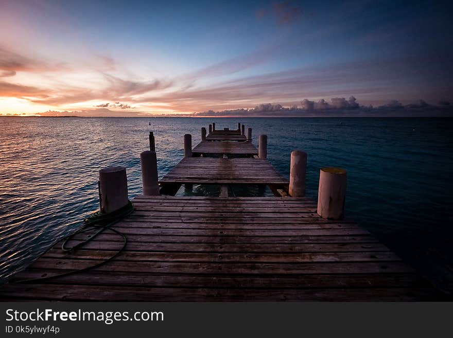 Wooden pier on the sea during sunset. Beautiful orange purple sk